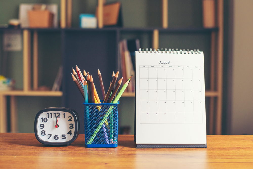 Kalender op bureau met pennenbakje en wekker